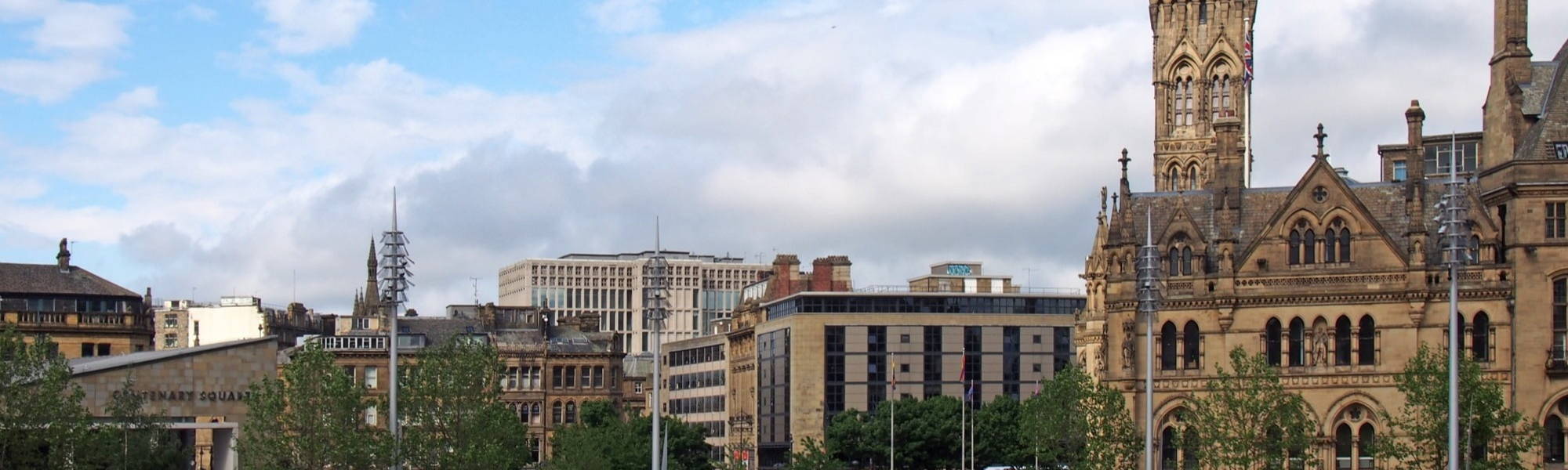 a cityscape view of centenary square and town centre in bradford west yorkshire with people sitting and walking past the city hall and main streets