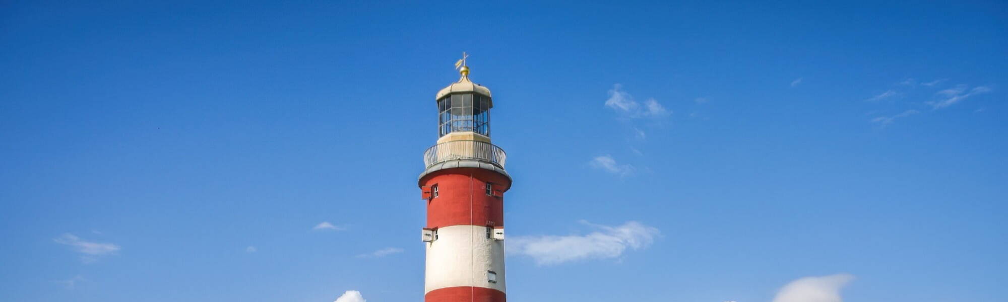 clear sky and a red and white lighthouse in Plymouth, Devon