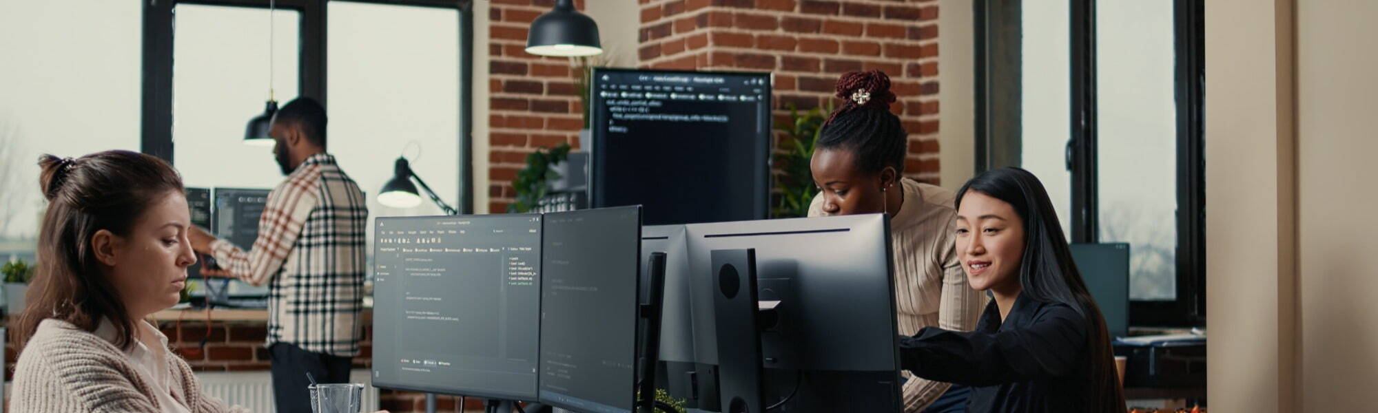 Software engineer typing source code on computer keyboard while colleagues sit down at desk for group project. App developer working in it startup company doing online cloud computing.